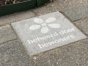 Stoeptegel met bloem-icoon en tekst beheerd door bewoners